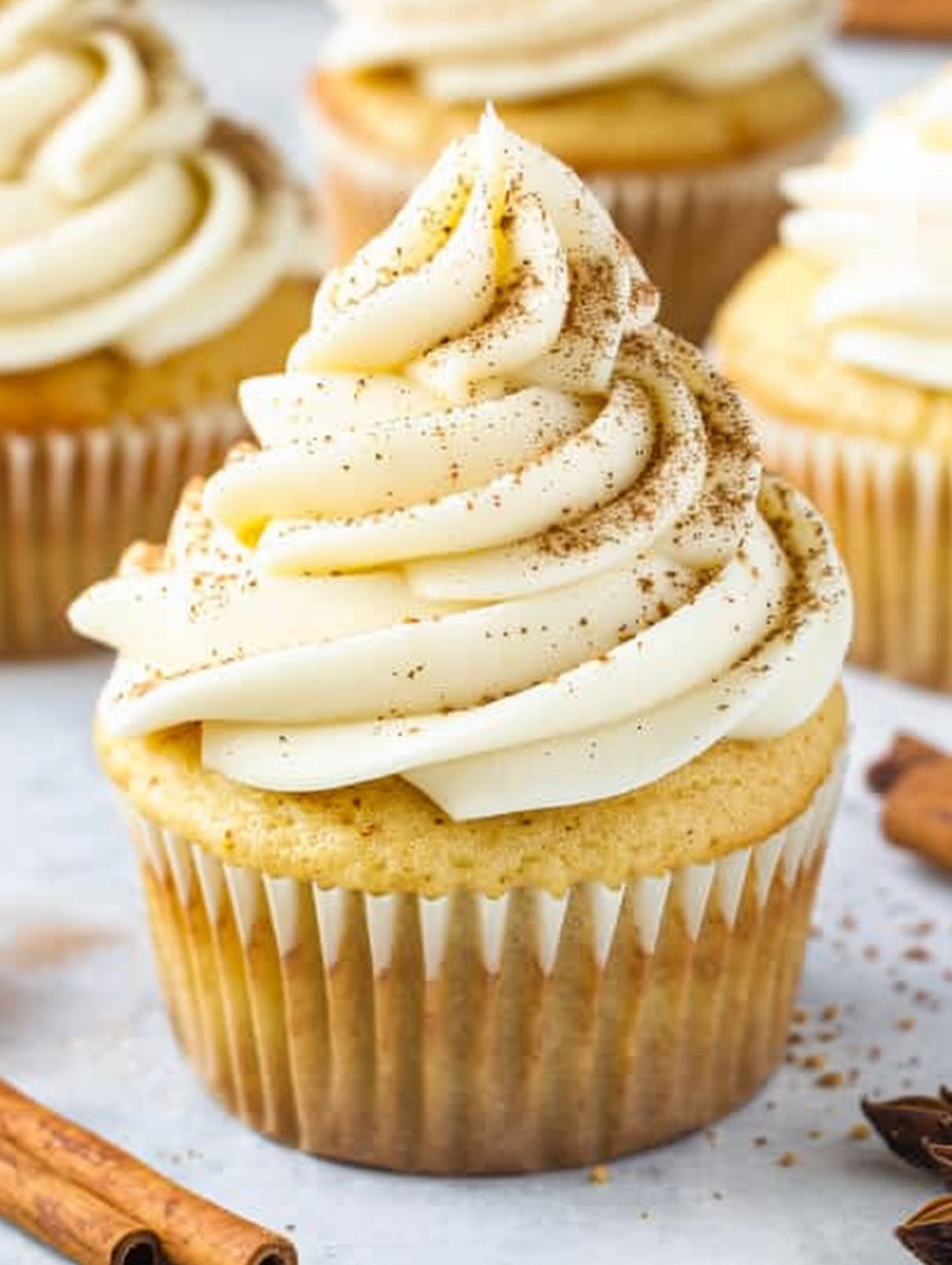 A cupcake with white frosting and cinnamon sprinkled on top.