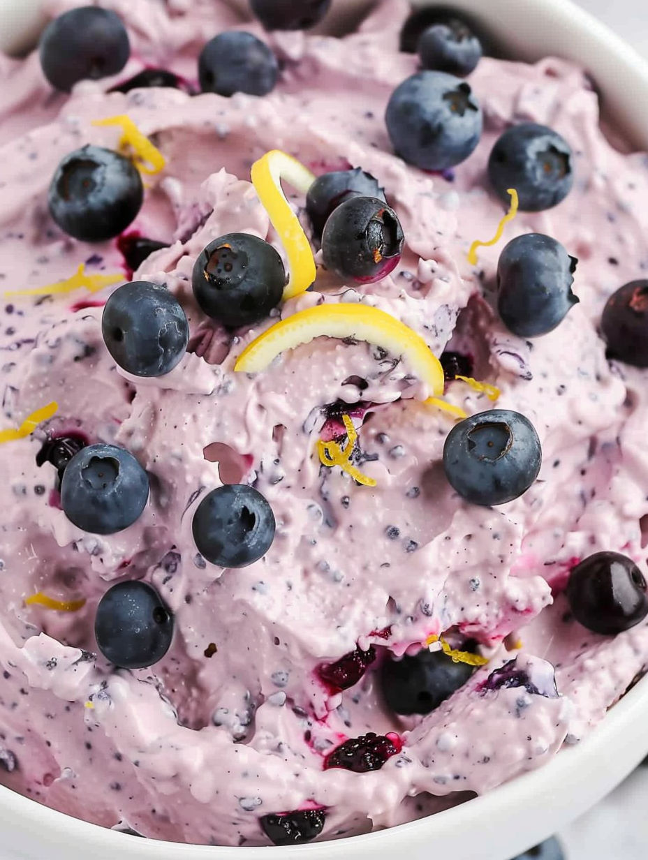 A bowl of blueberry fluff with blueberries and lemon.