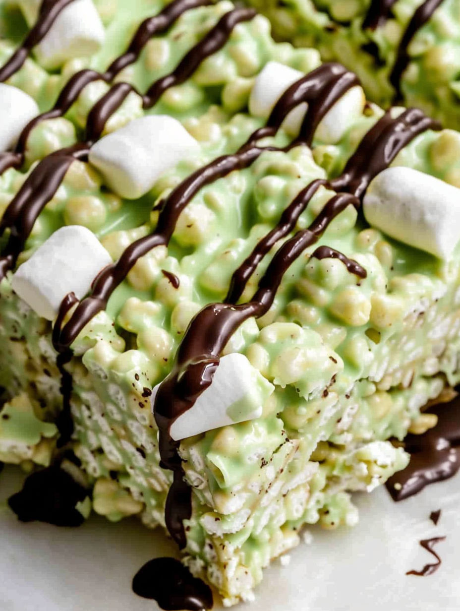A close up of a pistachio rice krispie treat with dark chocolate drizzled on top.