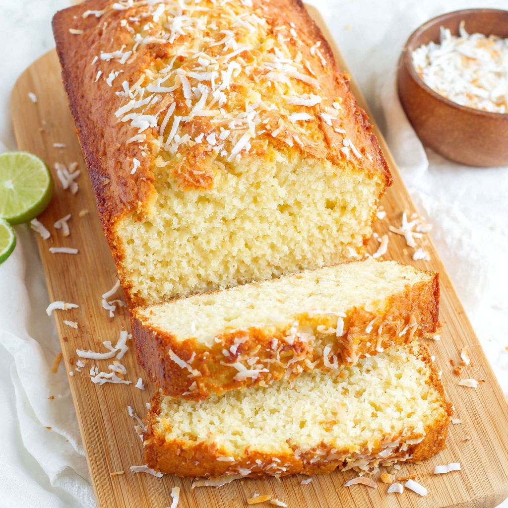 A slice of coconut cake on a wooden board.