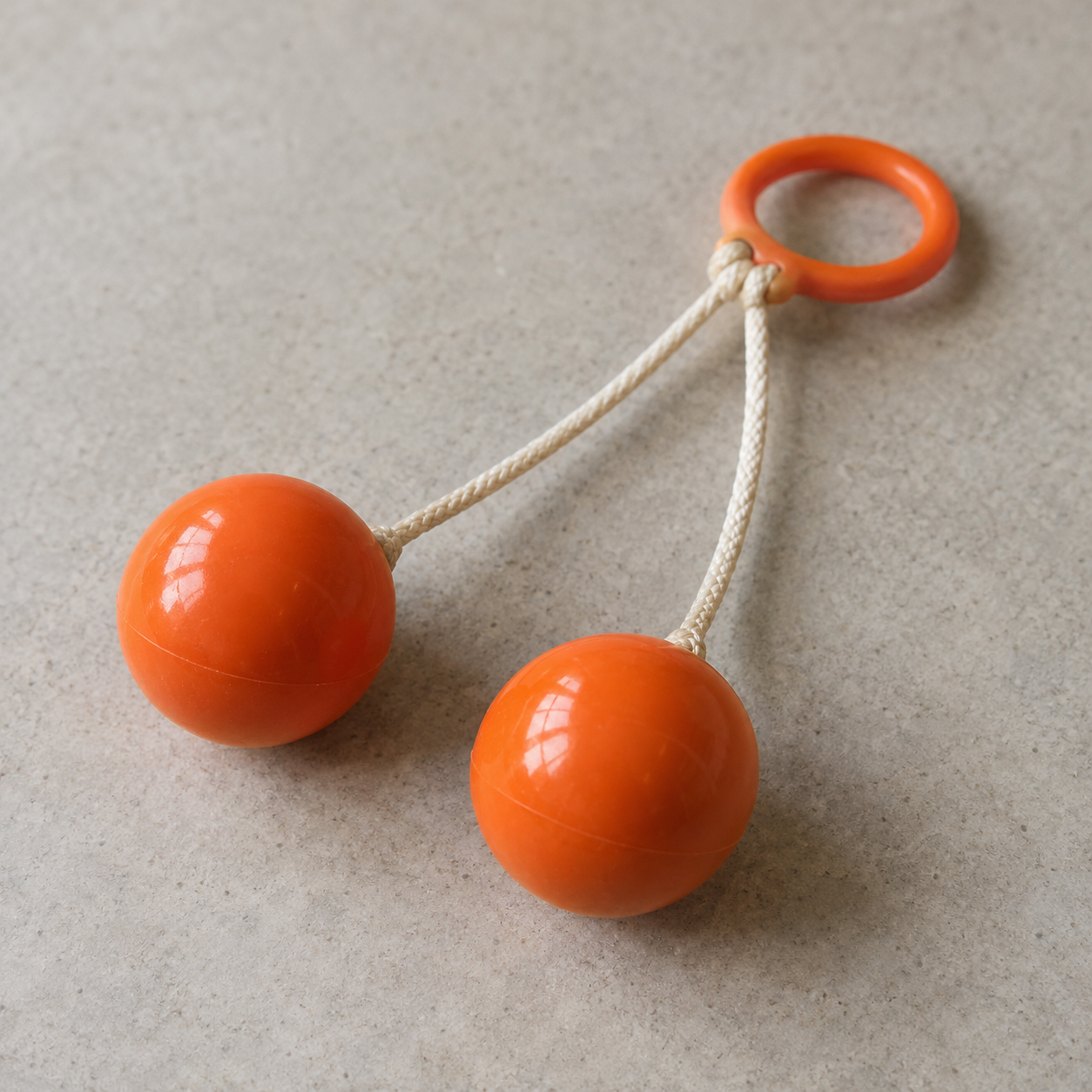 Orangefarbene Klick-Klack-Kugeln mit Schnüren und Ring auf neutralem Tisch