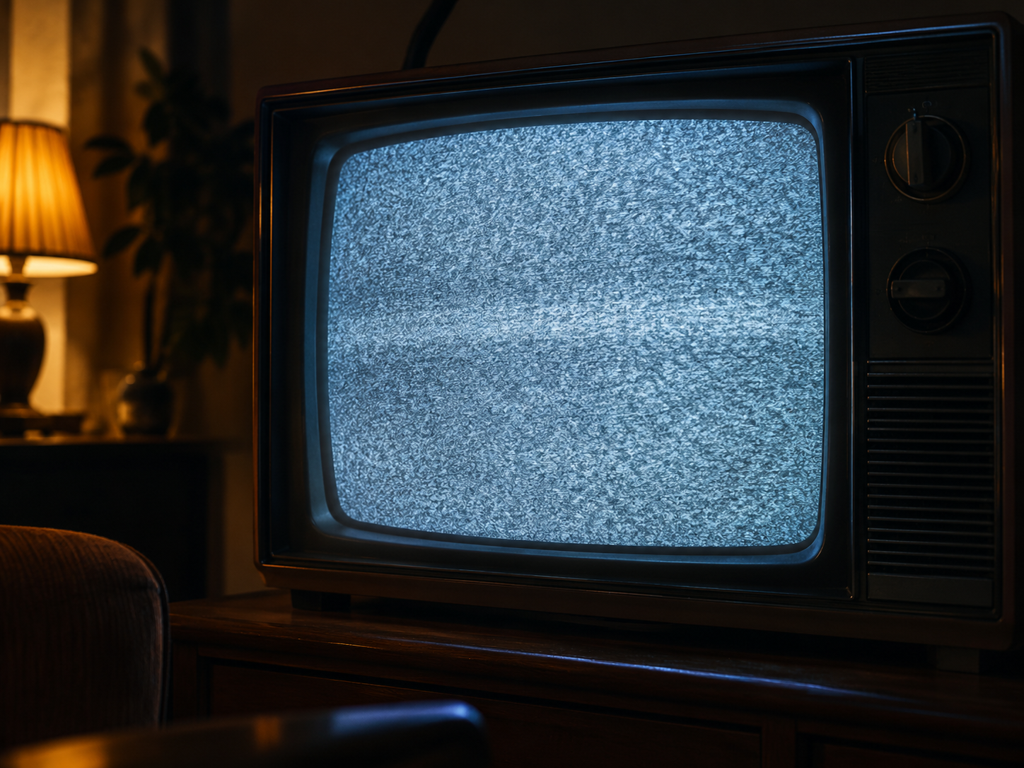Ein alter Fernseher zeigt nach Sendeschluss verrauschtes Bild in einem dunklen Raum.
