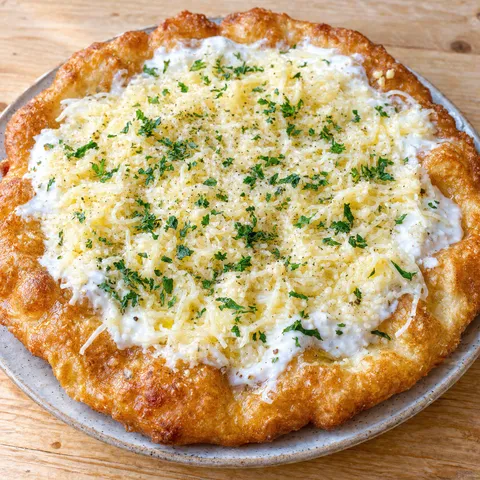 Ungarischer Langos mit Schmand, geriebenem Käse und Kräutern