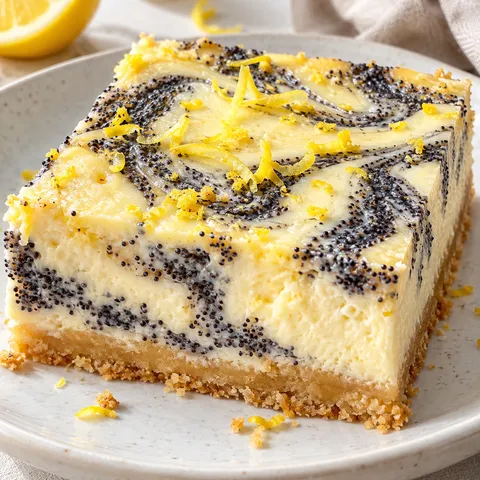 Zitronen-Mohn-Käsekuchen mit Mohnwirbeln auf hellem Teller