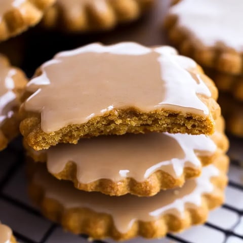Ein Stapel mit glasierten Keksen, bei dem einer zur Hälfte aufgebrochen ist, um die Füllung zu zeigen.