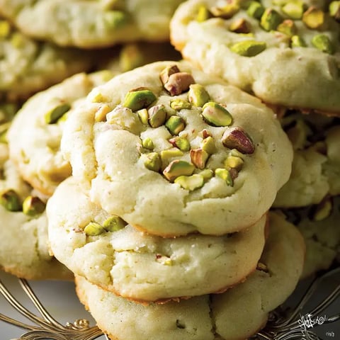 Ein Haufen weicher Kekse mit Pistazien, die auf einem goldenen Teller angerichtet sind.