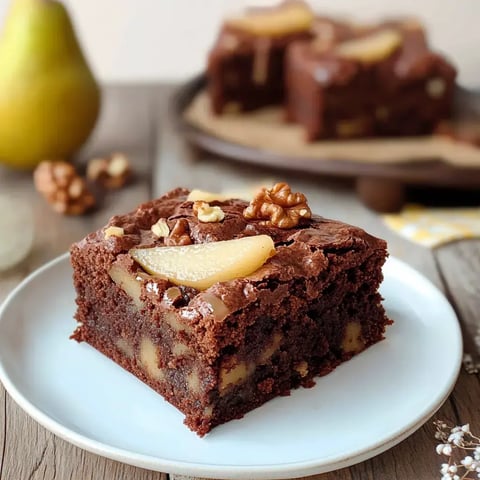 Ein Stück schokoladiger Kuchen mit Birnen und Walnüssen auf einem weißen Teller.