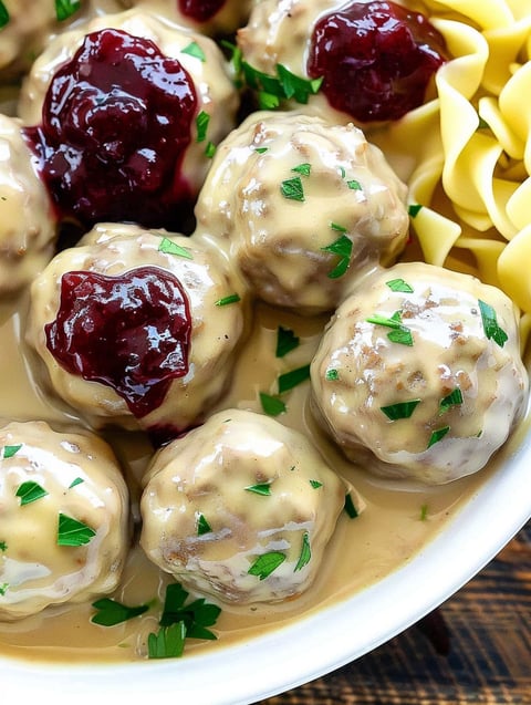 A plate of meatballs with sauce and green herbs.