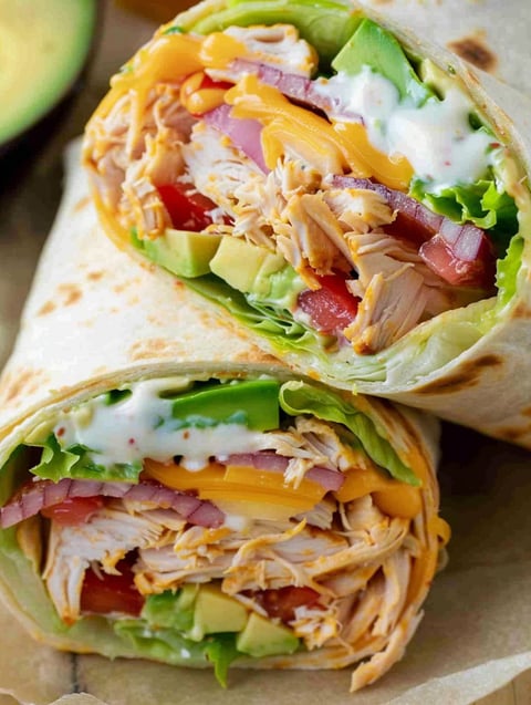 Two BBQ chicken wraps with lettuce and tomato.