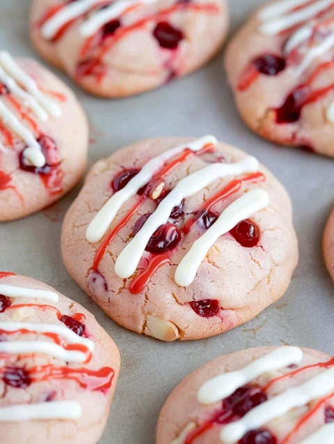 A close up of a cookie with white icing and cherries.