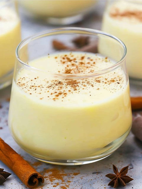 A glass of eggnog with cinnamon sprinkled on top.