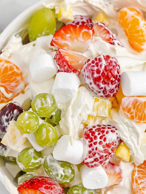 A bowl of fruit salad with strawberries, grapes, and oranges.