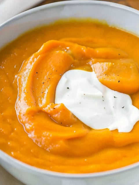 A bowl of creamy potato carrot soup.