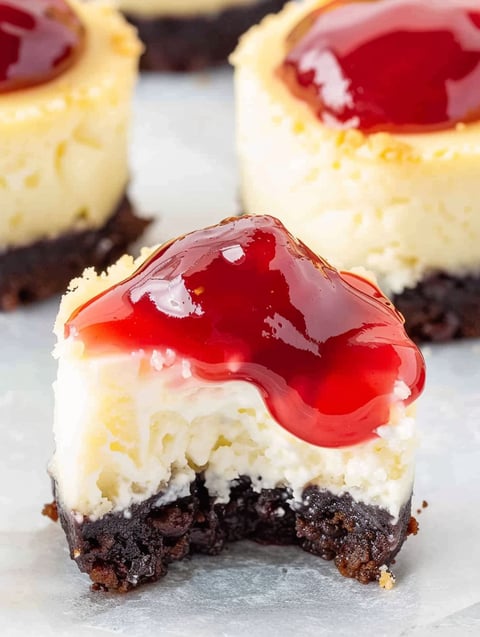 A slice of mini cherry cheesecake with a cherry on top.