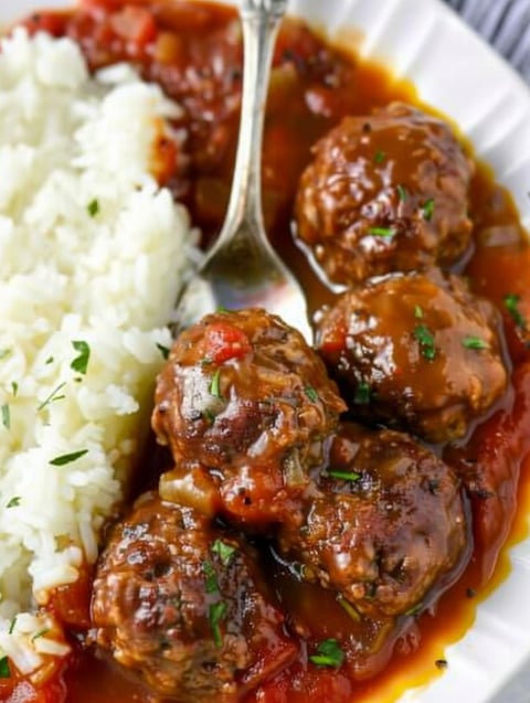 A plate of meatballs with gravy on a white plate.