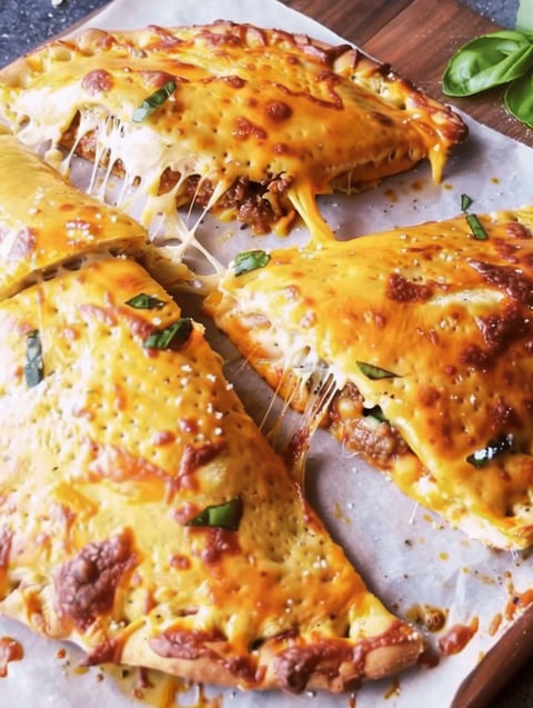 A slice of cheese and meat calzone.
